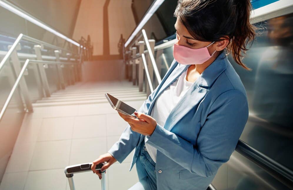 alto angulo de mulher com mascara medica e bagagem usando smartphone no aeroporto durante a pandemia 23 2148789874