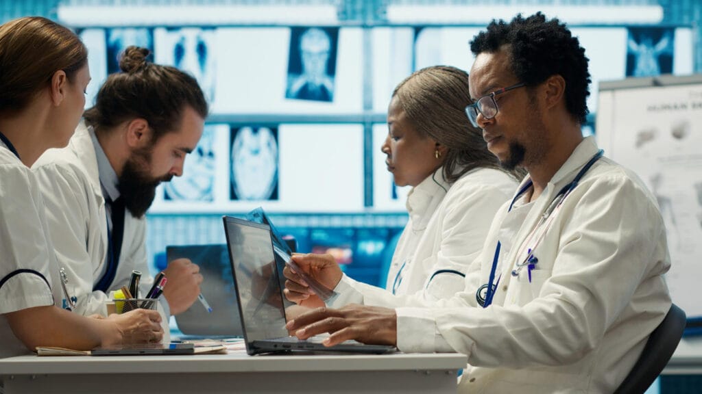 Equipe médica colaborando em laptop para Horizonte Europa para médicos em Portugal