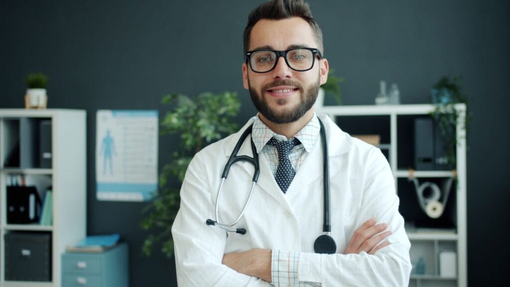 Reconhecimento Médico brasileiro em Portugal 18 Médico formado no Brasil de jaleco e estetoscópio em consultório, planejando trabalhar na Europa e na Itália