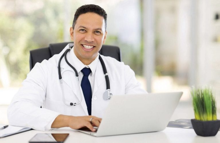 medico-sorrindo-sentado-digitando-computador-1024x683